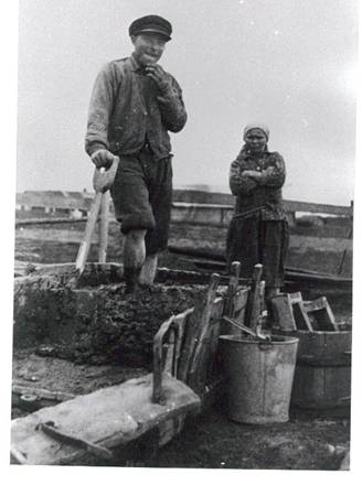 image048.jpg -  Foto Samuli Paulaharju början 1930-talet Fabian Henriksson, senare Elenius 1905-1979 och Lempi Junkka 1898-1975 bodde i början 1930-talet tillfälligt i Axel och Julia Uusitalos kammare på Näkkälägården. Fabian och Lempi hade beslutat att bygga eget hus på Erkkintermä. Här förbereder de med att tillverka tegel till murstocken på gårdsplanen hos Axel och Julia. Bakom syns Marttigården. 1935 kunde familjen flytta till det nybyggda huset på Erkontermä och blev granne till Samuel och Elsa på Pirjonpalo när de flyttade från Ollagården 1939 till nybyggnaden. Älven skymtar bakom.