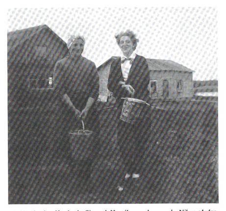 image054.jpg -  Här står Rolands mor Agnes Mukka 1911-2004 från Tuollavaara gift med Sigvard Henriksson 1912-1998 från Nikugården. Till höger Anges syster Anna på besök i Lainio Det lägre huset är den gamla Nikugården som nu är riven. Den stod på en liten backe nära vägskälet vid färjeläget. Älven syns lite där bakom. Agnes och Sigvard bodde på Nikugården innan de byggde nytt under 1950-talet. Senare hade Sigvard snickeriverkstad i högra delen av huset. I den vänstra delen bodde Sigvards bror Oskar med hustru Fanny Jakobsson några år. De flyttade senare till Tuollavaara. Huset byggt troligen av Sigvards farfar Nils Henrik f. 1846 eller av Nils Henriks bror Johan Erik f. 1843 En ännu äldre Nikugård brann ner under Erik Olofssons tid, far till bröderna som nämns ovan. Bild från Lainioboken. Fotograf Roland Henriksson.