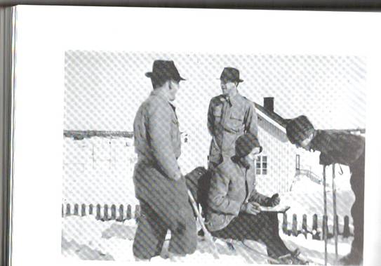 image055.jpg -  Bild 1950-talets början. På vintrarna anordnades skidtävlingar i Lainio. Sittande Oskar Henriksson 1918-1967 var en av dom som anordnade tävlingarna. Då bodde Oskar och hustrun Fanny på Nikugården. Den tävlande Helmer Olla, senare Granstål f. 1929 kollar tidsåtgången för honom med Oskar. Till vänster Otto Pudas, senare Elfgren, 1918-1979 och Otto Elenius 1918 tittar på tävlingen. Otto Elfgren kom att bo i Stockholm. Otto Elenius blev Kirunabo, Helmer Lainiobo efter en sväng i Kiruna på några år och Oskar flyttade till Tuollavaara på 1950-talet. Gamla folkskolan bakom. Bild från Lainioboken.