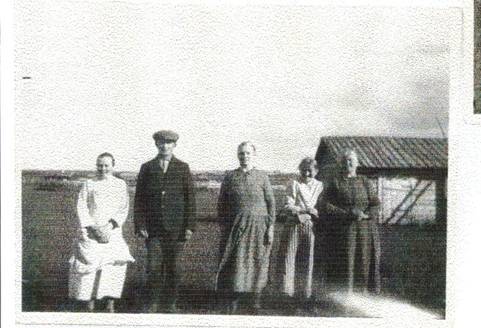 image081.jpg -  Nu är Natanael med sällskap på Ollagården. Karl var en flitig fotograf. Landsvägen till Lainio var bara några år gammal så det väckte säkert en viss uppståndelse när sällskapet kom farande med bil på Ollagården. Från vänster Natanaels bror Isaks 1861-1939 dotter Eugenia 1893-1937, sedan osäkert om det är Natanaels brors Eriks 1849-1936 söner Levi 1895-1980 eller Samuel 1902-1980 som står där, kan även vara Isak 1893-1976 en bror till, Natanaels bror Stefanus hustru Teresia 1877-1957, Isak Ollas 1893-1976 hustru Hulda 1891-1978 och sist Natanaels hustru Hilma 1861-1938. Bakom syns vedboden i Ollas uthuslänga. Då var det väldigt kalt i byn alla träd var nedhuggna.