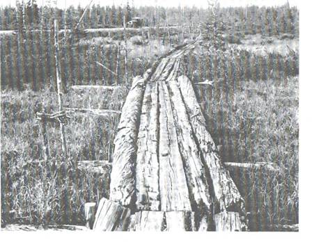 image107.jpg -  Foto G Ullenius 1930. Bild från Lainioboken. Detta är vägen sommartid till Lainio fram till ungefär 1927. Landsvägen blev klar 1927. Landsvägen är 3 år gammal. Personbilen syns på landsvägen. Antagligen fotografens bil. Stockarna fanns fortfarande kvar när vi barn sprang på dem under 1940-talet. Ibland hade man upp till 7 längsgående stockar. När landsvägen var klar började Posti Ville använda cykel för posttransport. Gångstigen en bit bortom sjön Kotijänkäjärvi. Stigen gick till Vivungi för att fortsätta till Kuoksu och vidare till Vittangi, avståndet var 24 km. I Vaikkojärvi fanns en gångbro över den smaladelen av sjön.