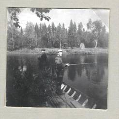 image128.jpg -  Det fanns tid för fiske i Saangijoki under stämplingen 1957. Rune Eriksson längst bak och Gunnar Eriksson. Det var dåligt med napp säger texten under fotot. Fortfarande år 1957 slog man stränderna efter bäcken. En hässja syns på andra sidan bäcken.