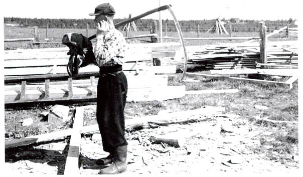image157.jpg -  Isak Olla med lie. Det var klockstapelbyggnation i gång vid bönhuset. Bilden mitten 1950-talet. På andra sidan vägen korkeatermä, den gamla kornåkern.