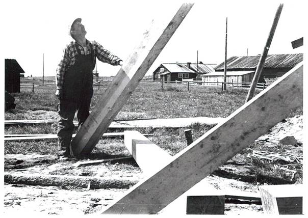image158.jpg -  Levi Zakrisson 1904-1980 arbetar med att bygga upp klockstapeln 1955. Till vänster syns en lada. Bakom Ollas uthus med Isaks ladugård och de gamla uthusen från Olla Erkkis tid.