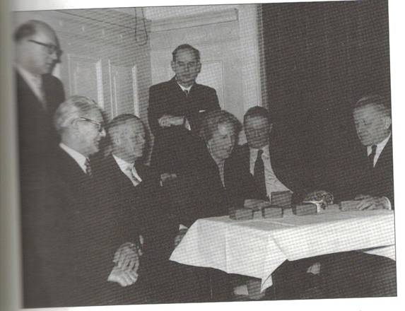 image184.jpg -  Bild från Elektriciteten i Luleå 100 år 1896-1996 av Kjell Lundholm. Andra mannen sittande från vänster är John Johansson, senare 1930-talet Järvfelt 1896-1965, född i Malmberget och son till Stefanus Johansson 1868-1928 från Ollagården och Teresia Koskenranta 1877-1957. Han var chef för Luleå elverk till 1961. Här utdelning av klockor under 1950-talet. Det var John som hjälpe Isak Olla att sälja smöret som hunnit härskna som Isak hade med från Ollagården när han körde med häst och släde till Malmberget för att sälja bl. a smör omkring 1915. Smöret köptes upp av ett bageri. Isak övernatta hos sin farbror Stefanus som hade flyttat till Malmberget 1893 från Ollagården i Lainio för att arbeta i gruvan. John gick Tekniska Elementarskolan i Örebro 1916-1919.